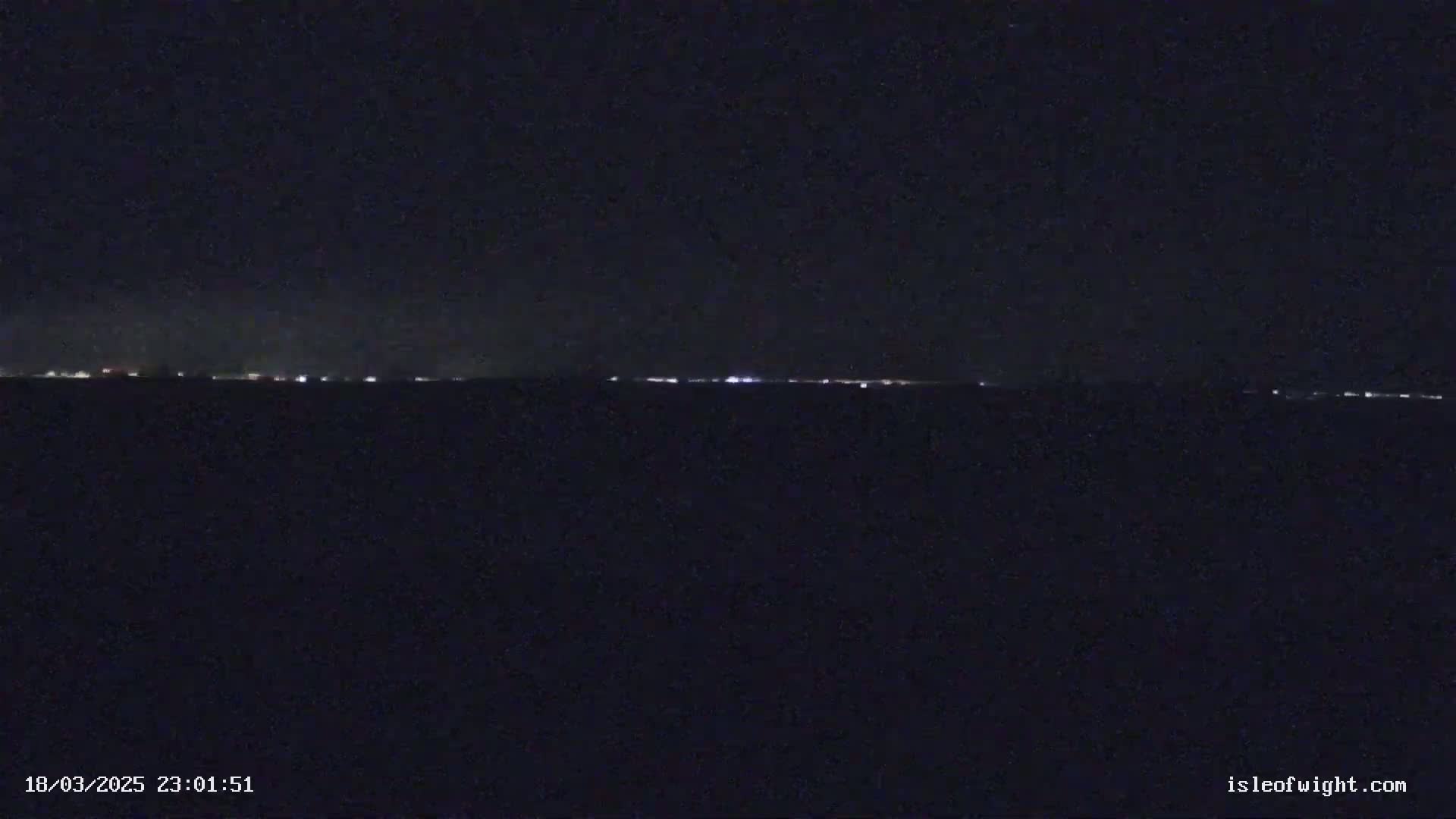 A long, thin line of distant lights is visible on a dark, nighttime horizon.