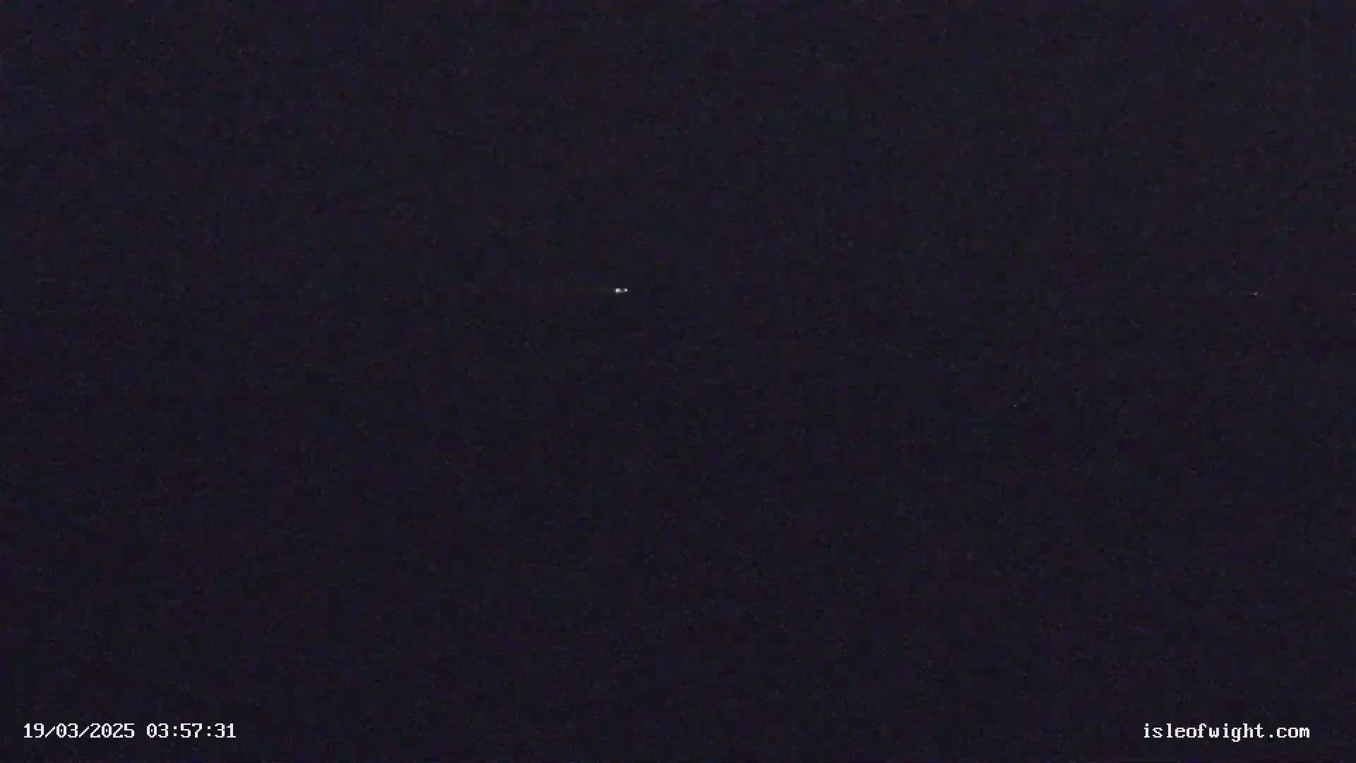 A dark, nighttime scene shows two small, faint lights in the distance.