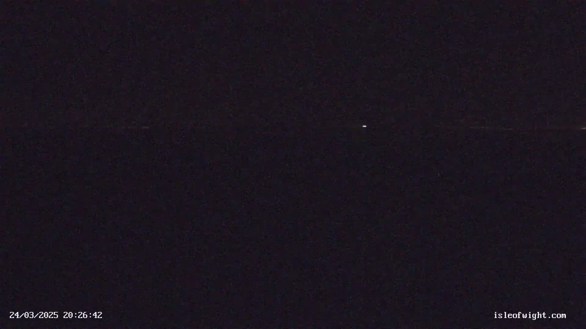 A single, faint light is visible in a dark, nighttime sky.
