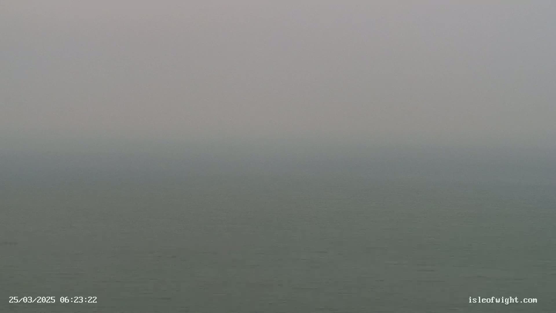 A body of water is visible under a hazy, foggy sky.
