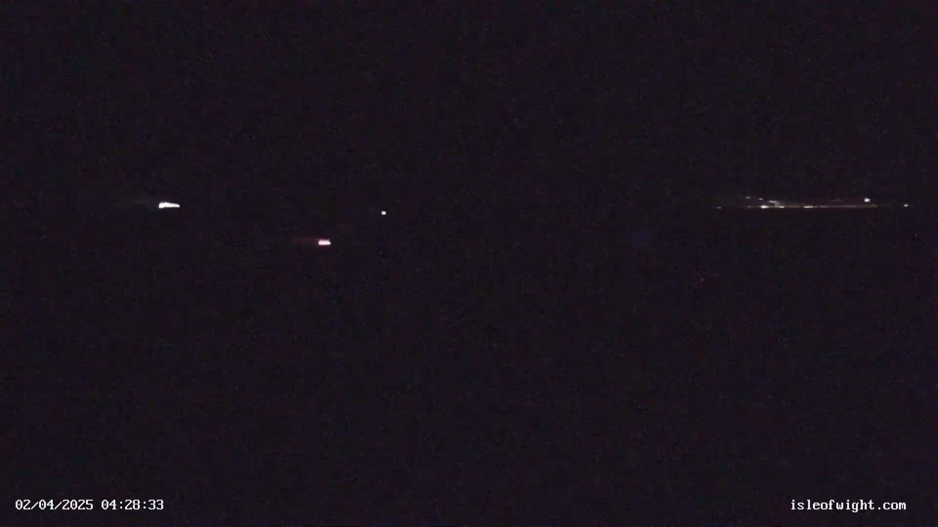 A nighttime long shot shows a few faint lights in the distance on the horizon.