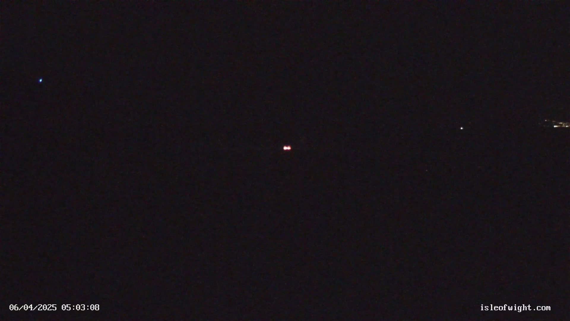 A dark night sky shows a few distant lights, including two close together and slightly brighter than others.