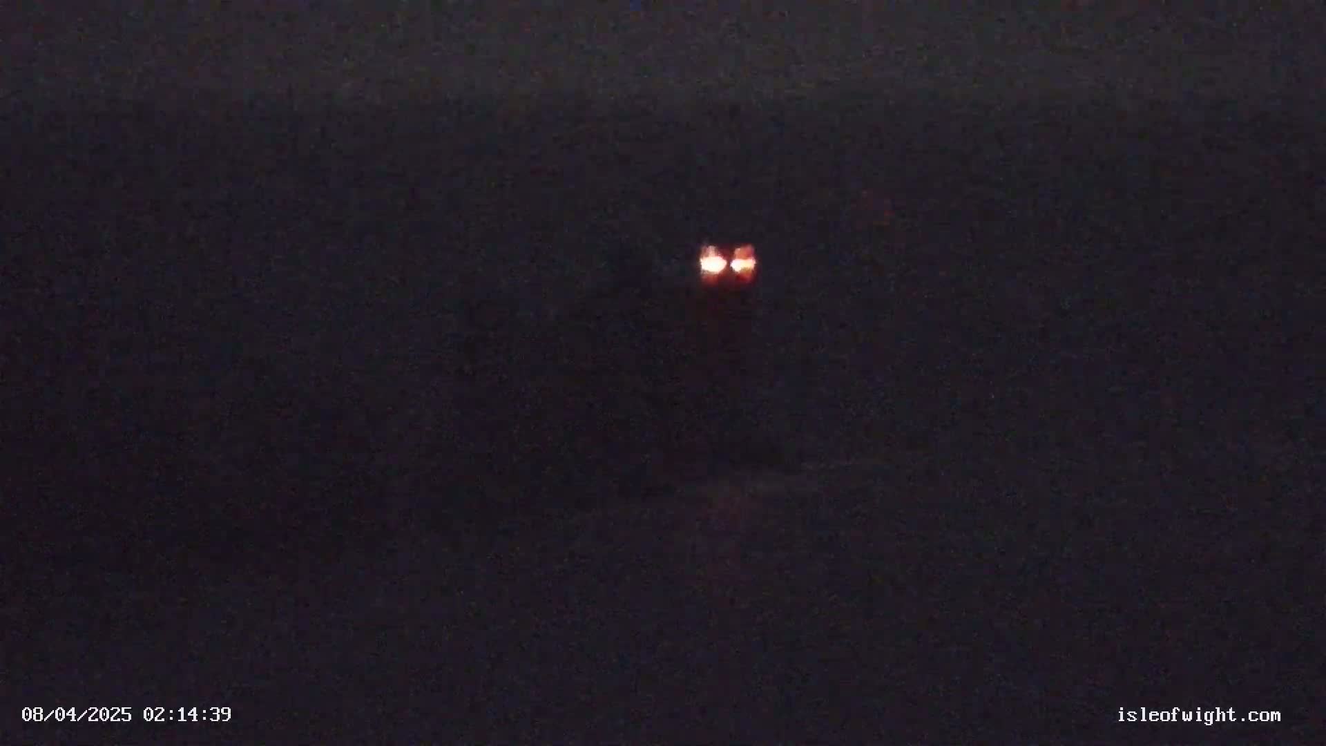 Two small, bright orange lights are visible in the dark night.