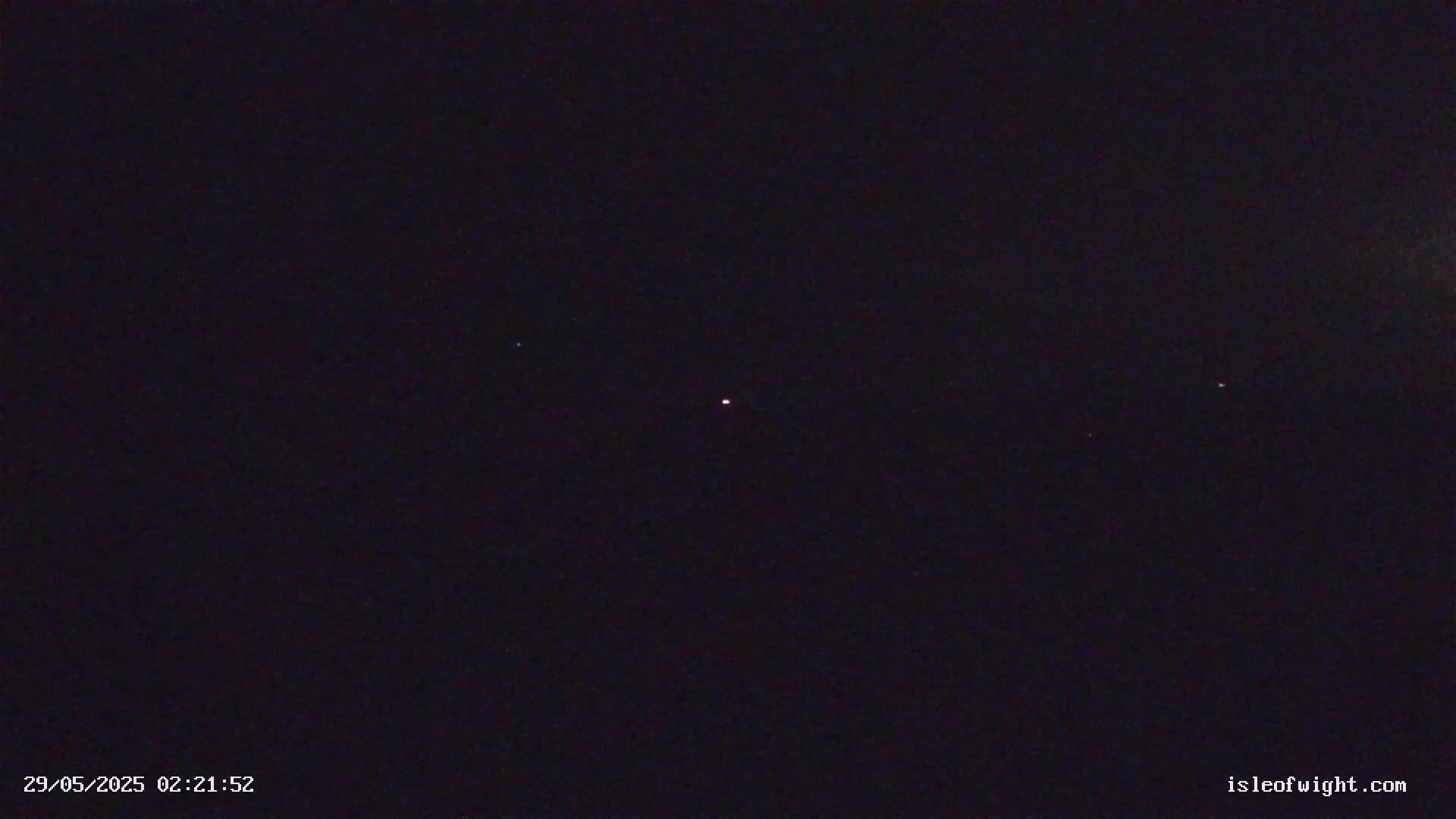 A dark night sky shows a few faint stars and a slightly brighter, reddish point of light in the center.