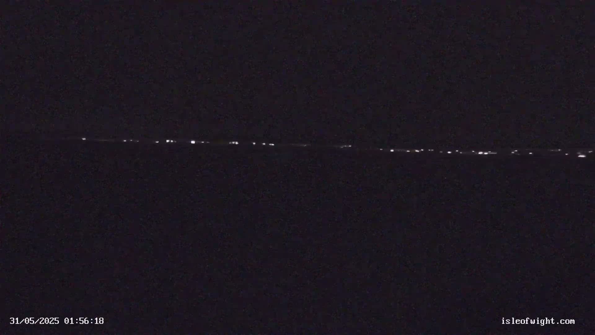 A long line of distant lights is visible on a dark, nighttime horizon.
