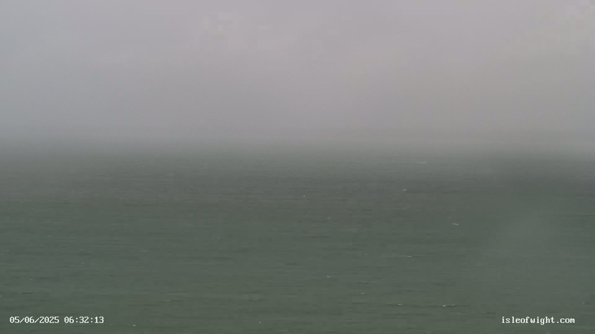 A dark-green sea is visible under a thick, gray fog.