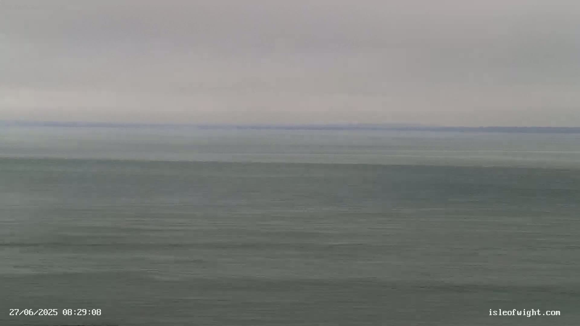 A calm, grey sea stretches to a hazy horizon under an overcast sky.
