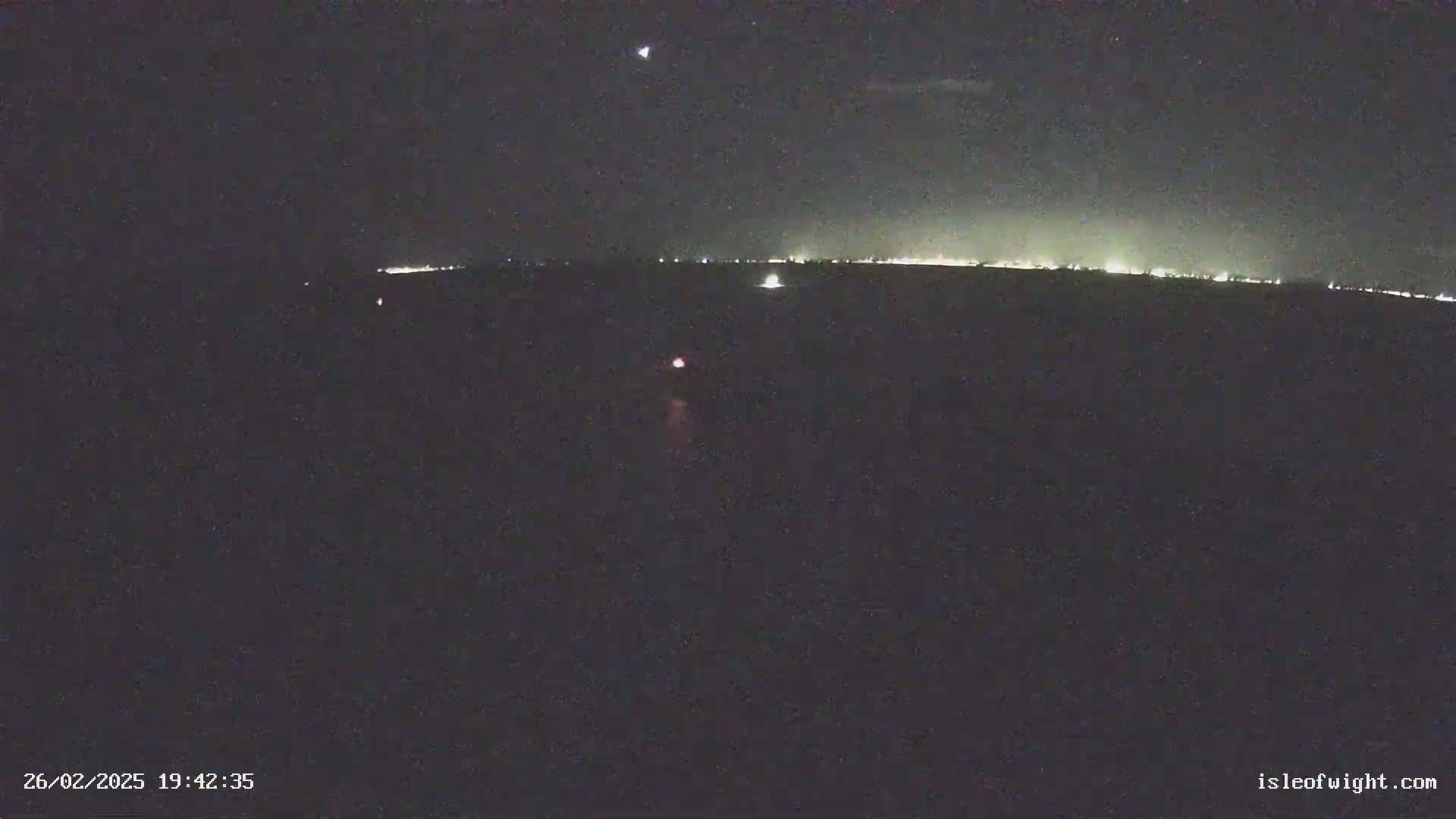 A nighttime long shot shows a distant line of lights on the horizon under a dark, clear sky with a single, bright star visible.