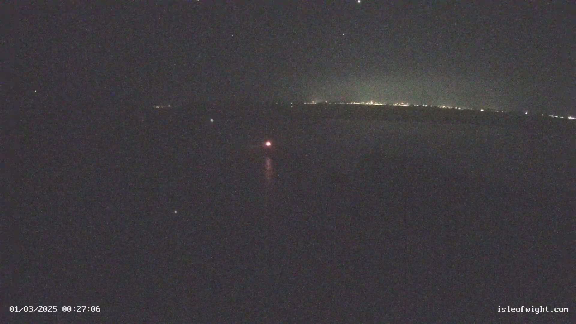 A nighttime long-exposure shot shows a faint reddish light streaking across a dark sky above a distant line of lights.