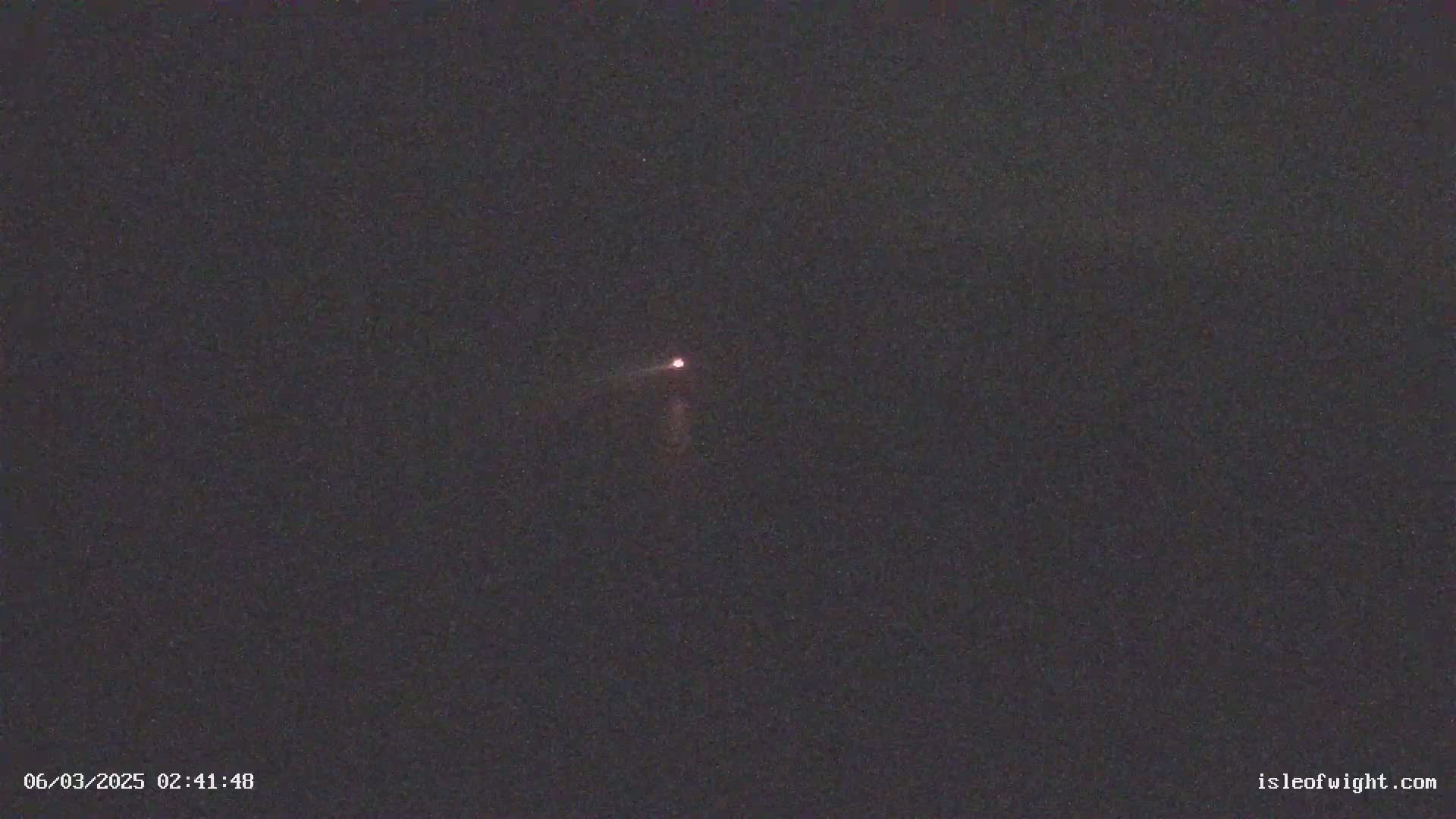 A small, faint light is visible in a dark night sky.
