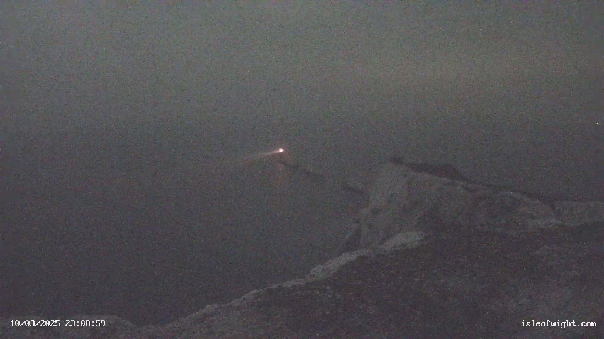 A faint, reddish light is visible in the distance over a dark, hazy landscape at night.