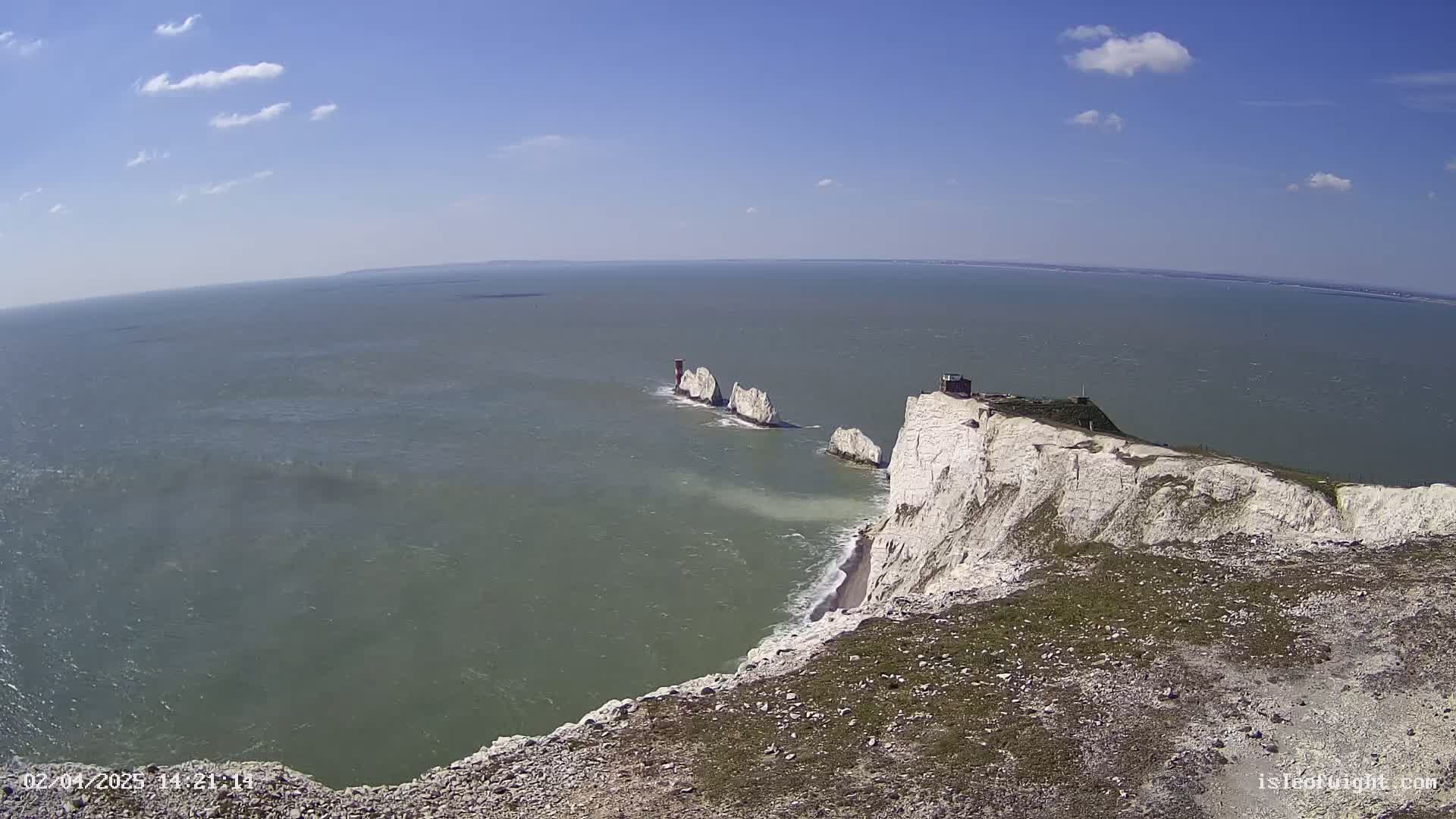 White cliffs overlook a body of water with several small, rocky islands under a mostly sunny sky with some scattered clouds.