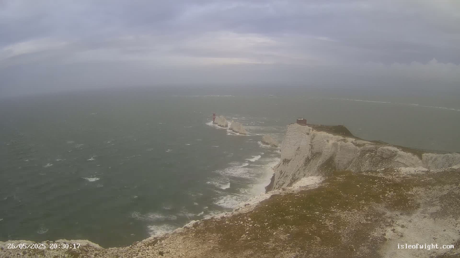 White cliffs meet a turbulent sea under a gray, overcast sky.
