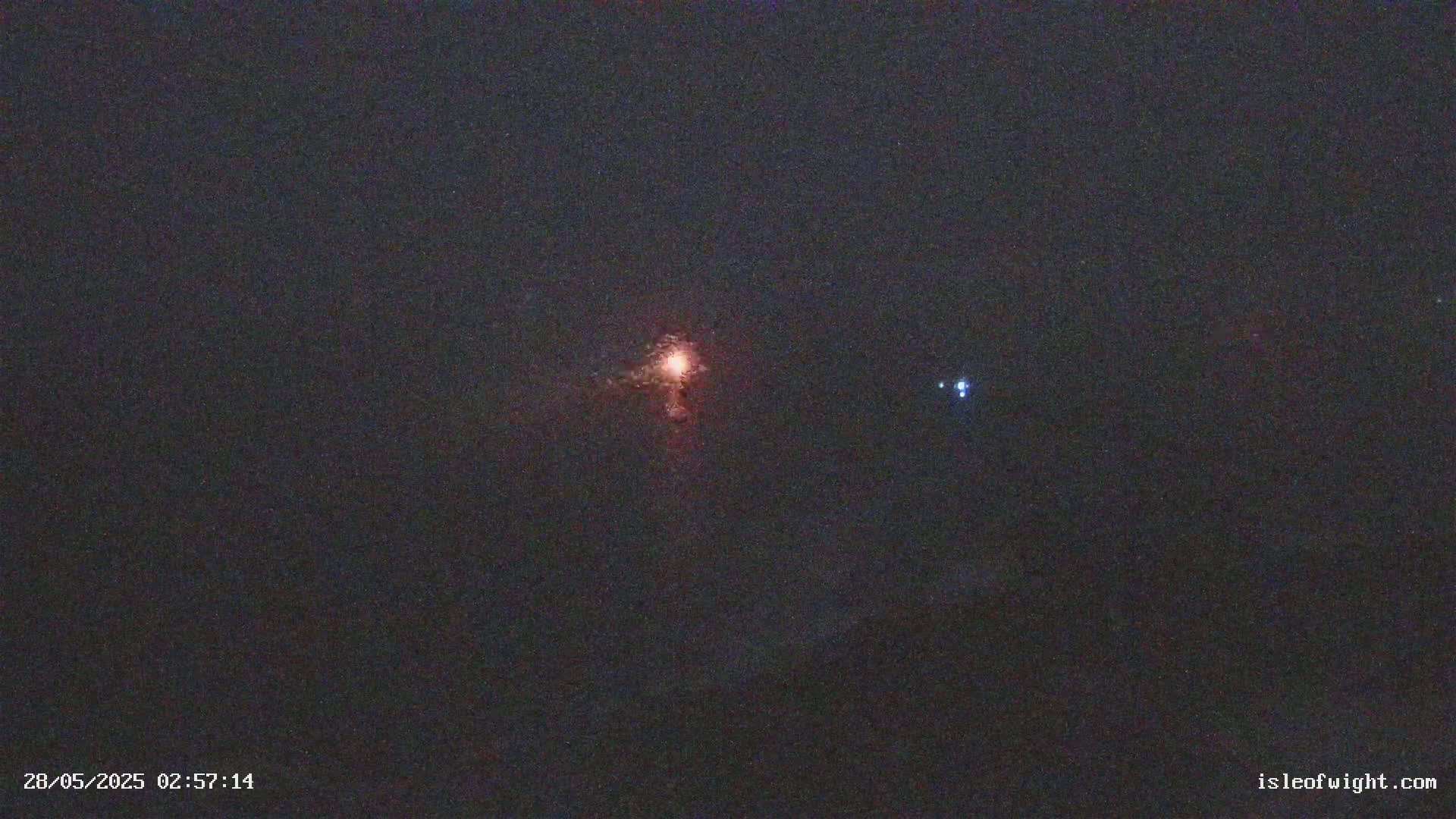 A nighttime image shows a bright orange light and a smaller fainter blue light in a dark sky.