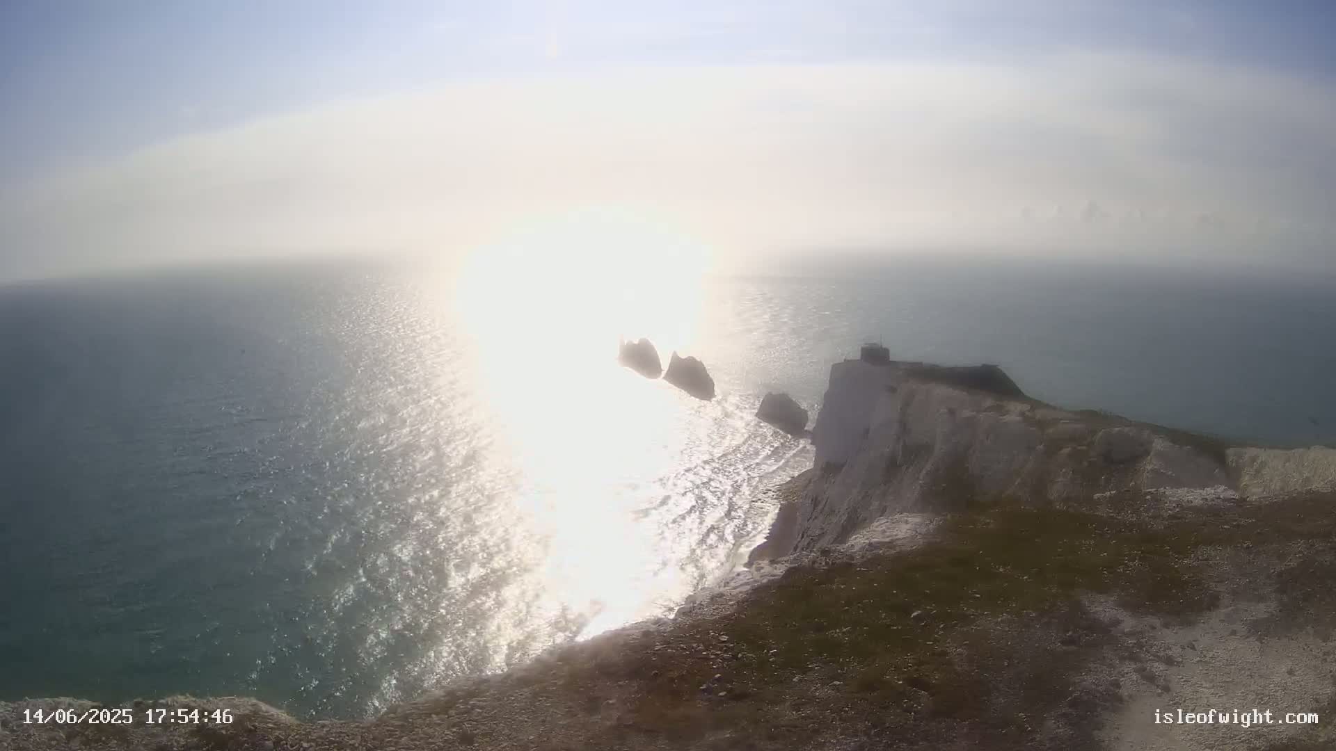 White cliffs overlook a hazy, sunlit sea with several small islands visible in the distance.