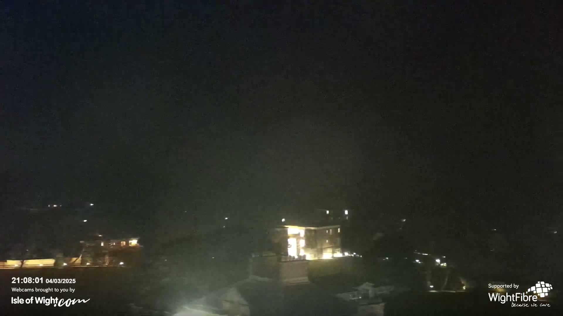 A nighttime view shows dimly lit buildings and trees under a dark sky.