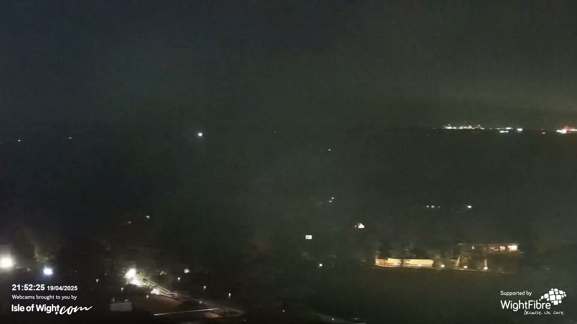 A nighttime long shot shows a dark landscape with sparsely scattered lights, under a cloudy sky.
