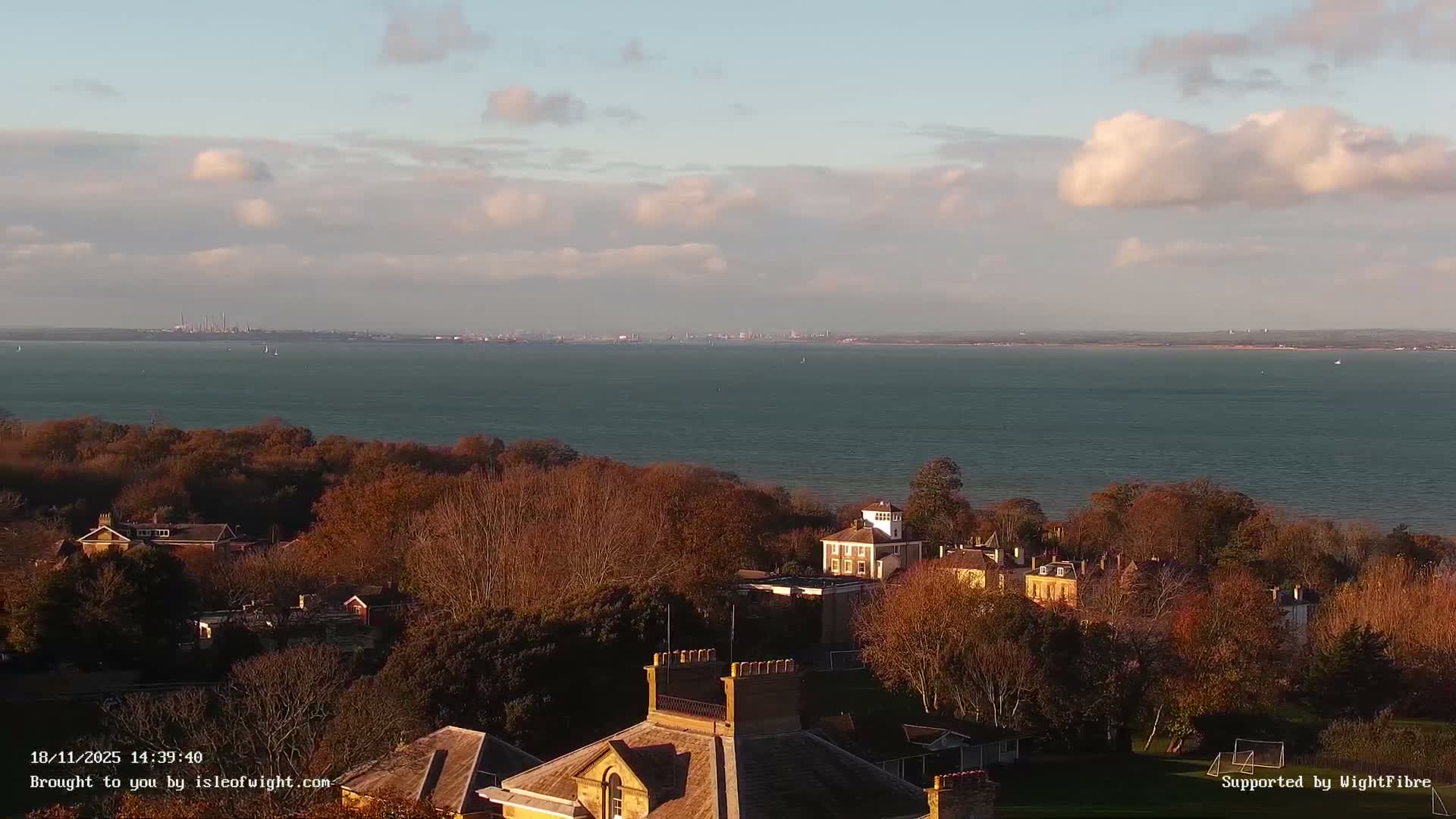 A nighttime view shows a dark body of water with a lit waterfront and distant city lights under a clear, dark sky.