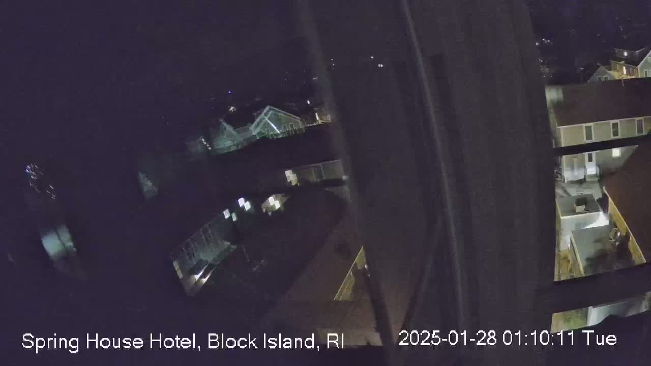 A nighttime, high-angle view from a window shows several illuminated buildings.
