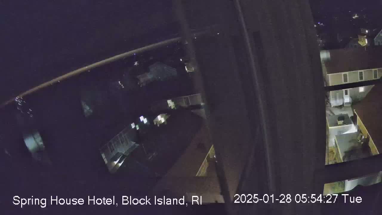 A nighttime, high-angle view from a window shows a dimly lit complex of buildings.