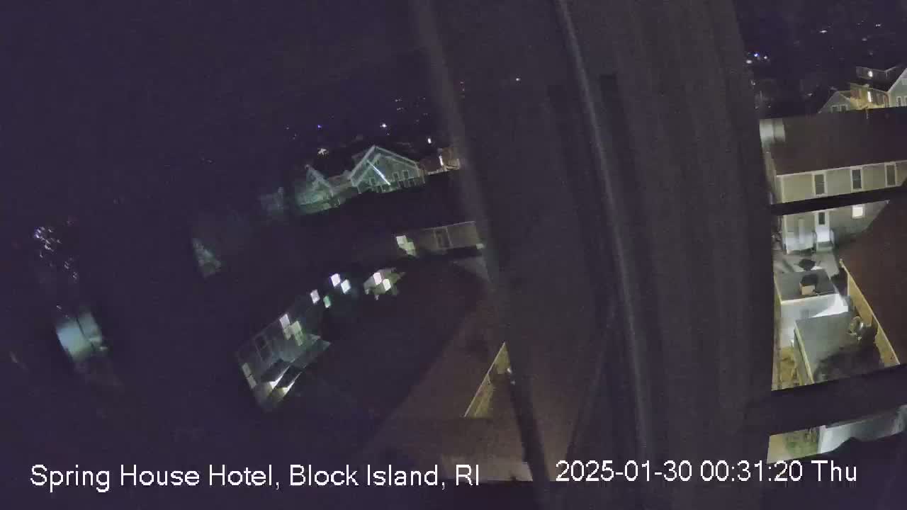 A nighttime, high-angle view from a window shows several buildings with dimly lit windows.
