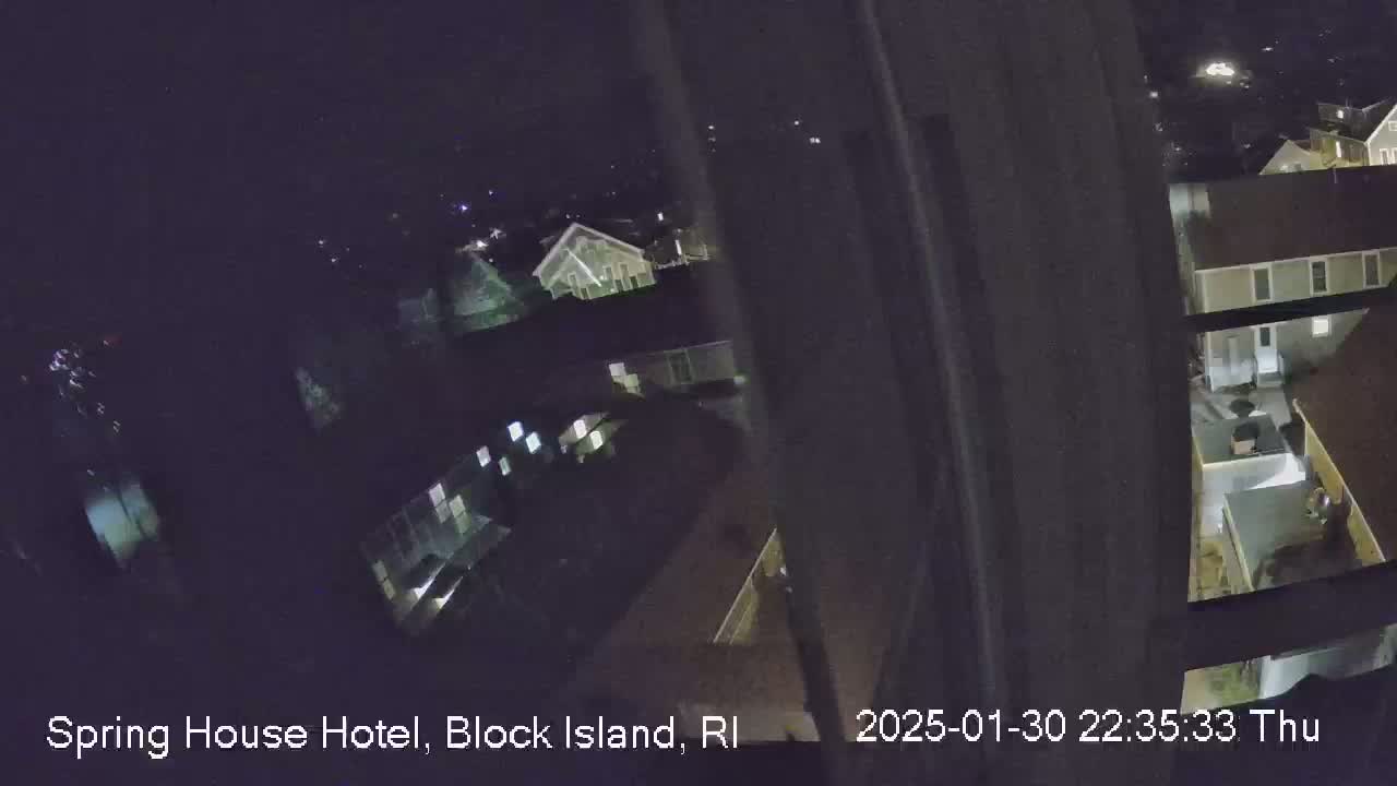 A nighttime, high-angle view shows a cluster of buildings lit from within under a dark sky.