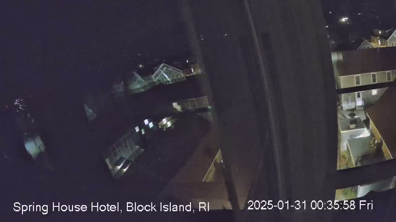 A nighttime, high-angle view through a window shows several low-lit buildings.