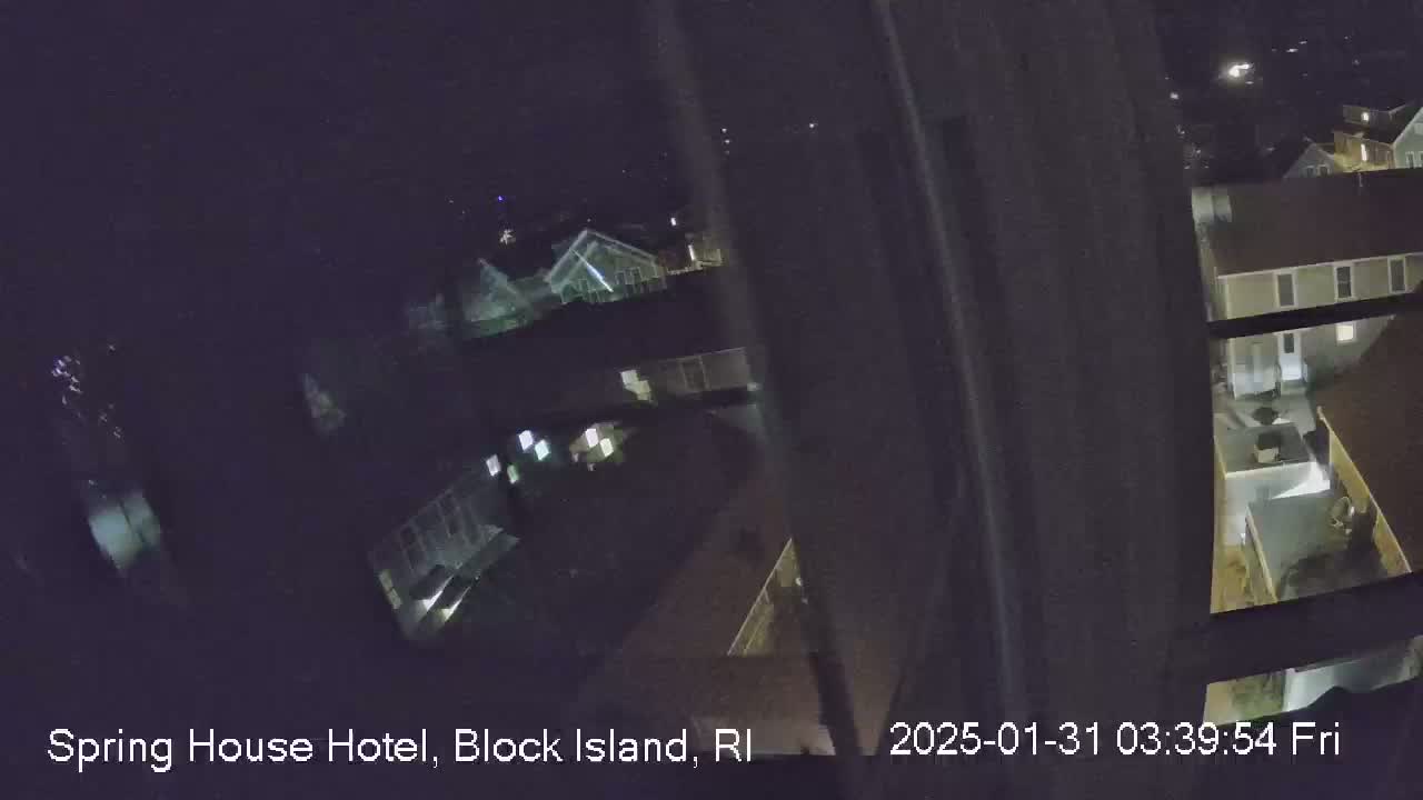 A nighttime, high-angle view from a window shows several buildings with illuminated windows.