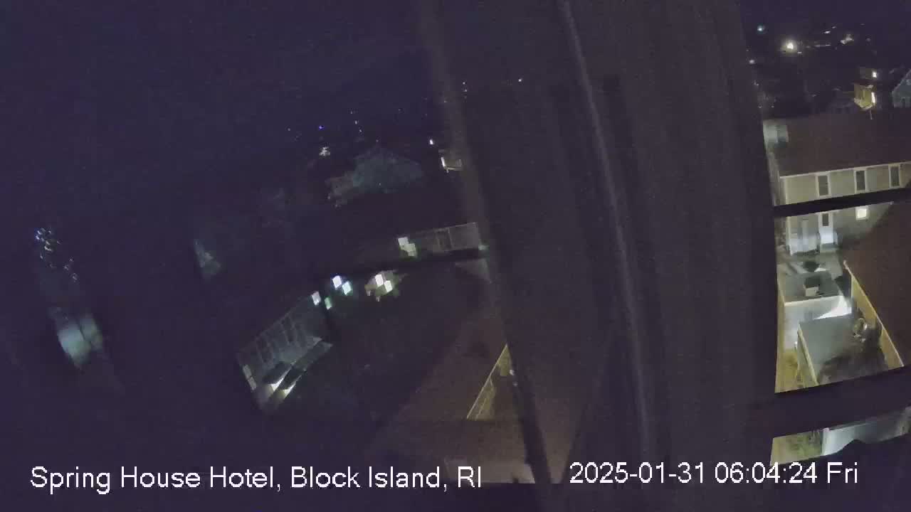 A nighttime, high-angle view through a window shows several buildings with some lights on.