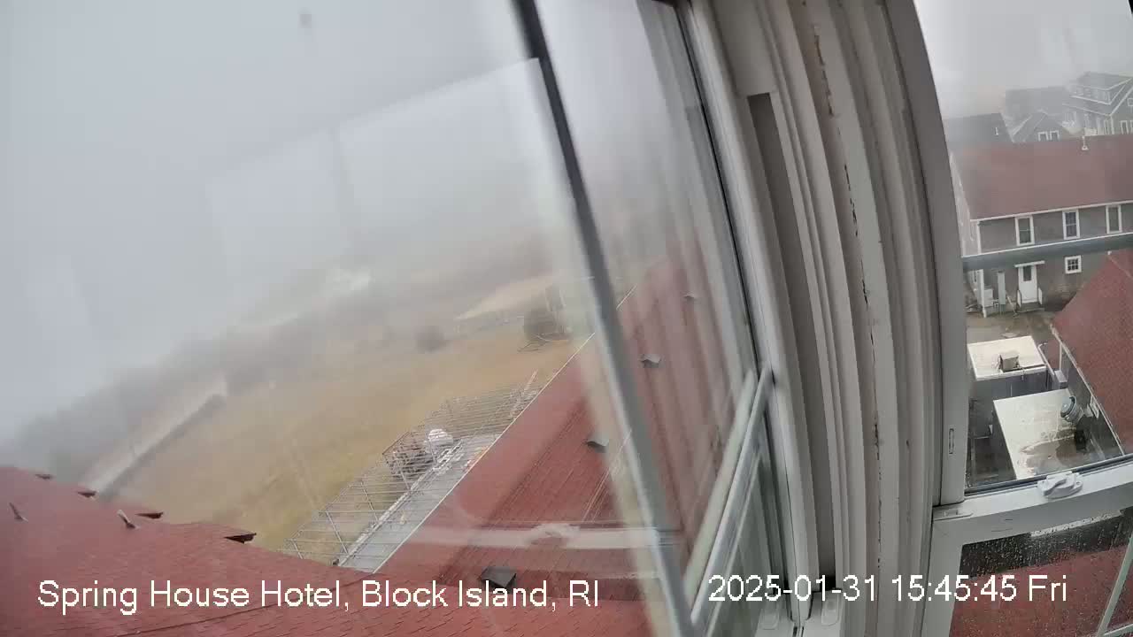 A foggy view from a window shows red rooftops and a partially visible yard.