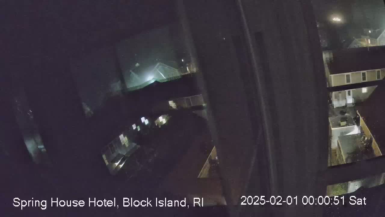A nighttime view from a window shows dimly lit buildings and a foggy or misty atmosphere.