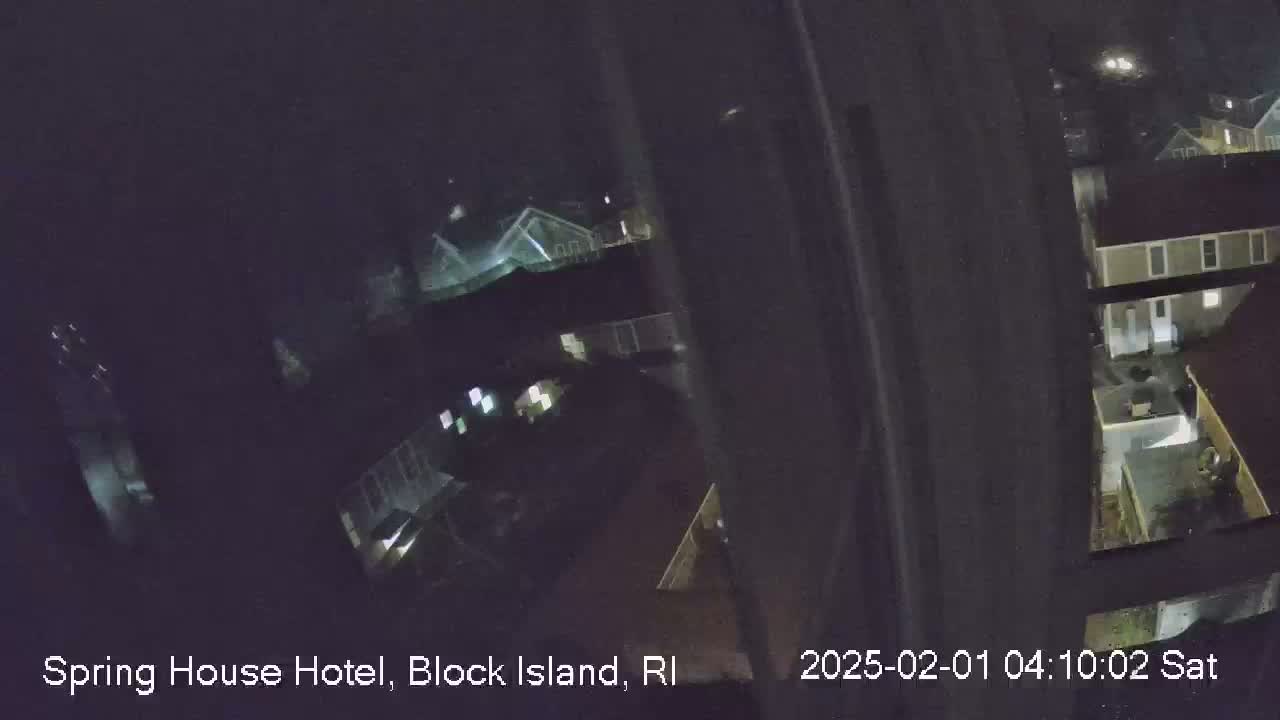 A nighttime, slightly blurry, overhead view shows several buildings and a dark road.