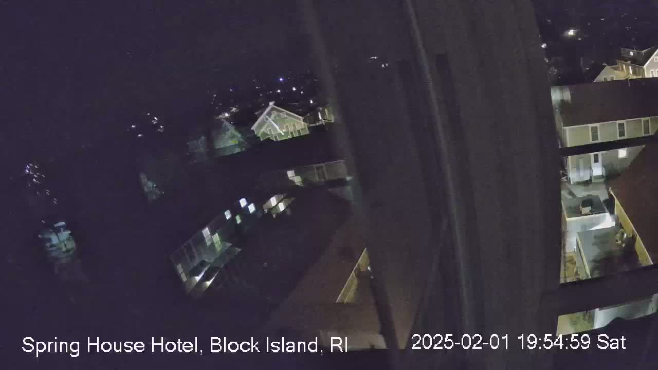 A nighttime, high-angle view shows several buildings illuminated with interior lights under a dark sky.