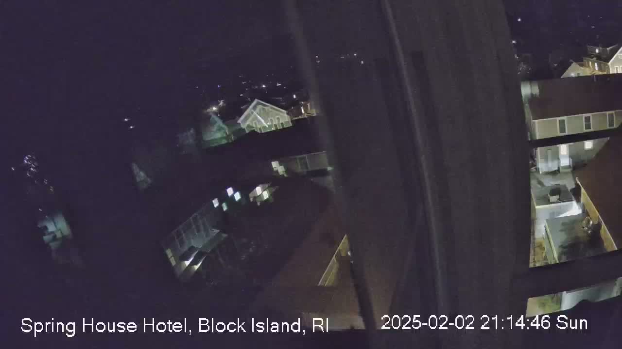 A nighttime, high-angle view shows a cluster of buildings illuminated by lights.