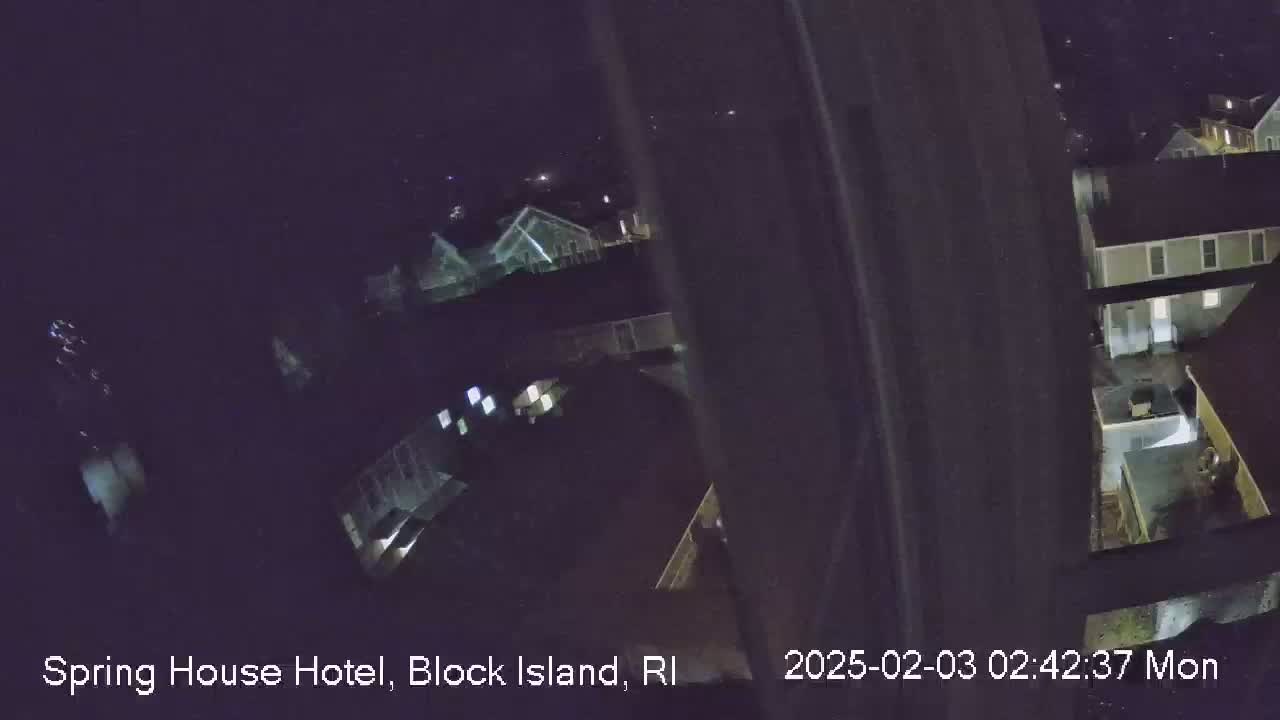 A nighttime, high-angle view shows several houses and yards from what appears to be a balcony or window.
