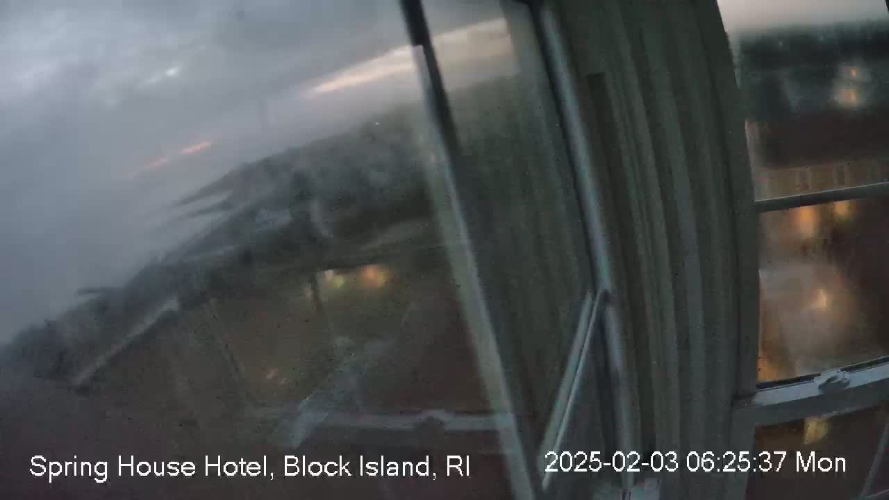 A rain-streaked window shows a blurry view of buildings and a dark, overcast sky.
