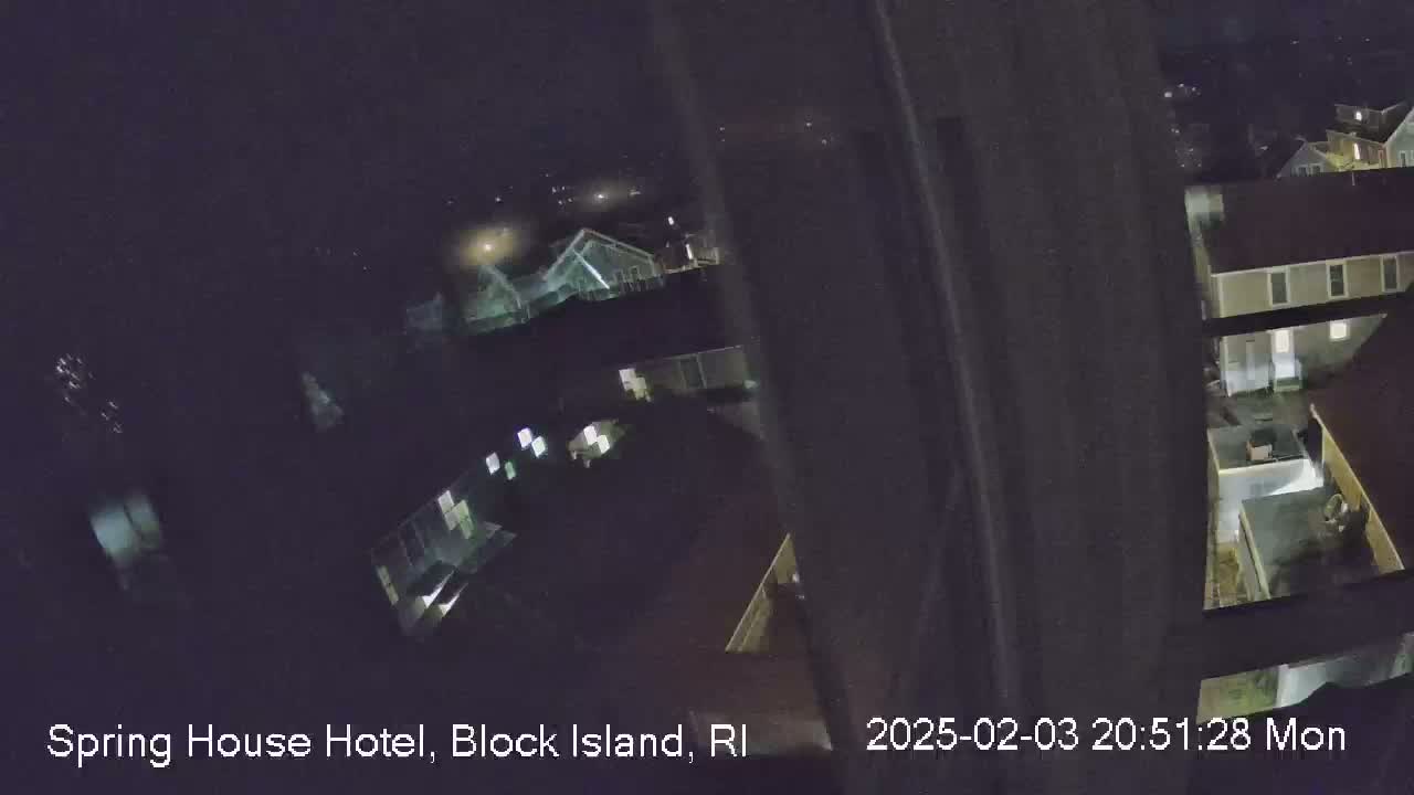 A nighttime, high-angle view shows several illuminated buildings and a dark expanse beyond.