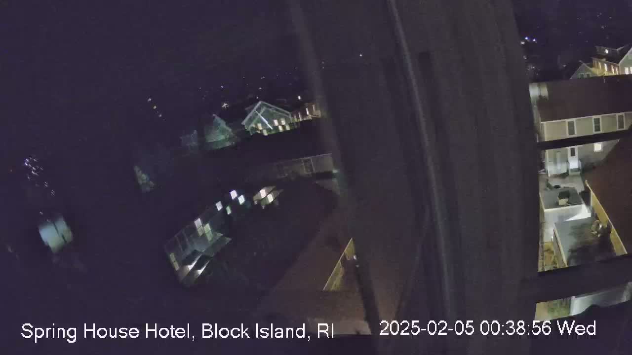 A nighttime, high-angle view from a window shows several buildings with illuminated windows.