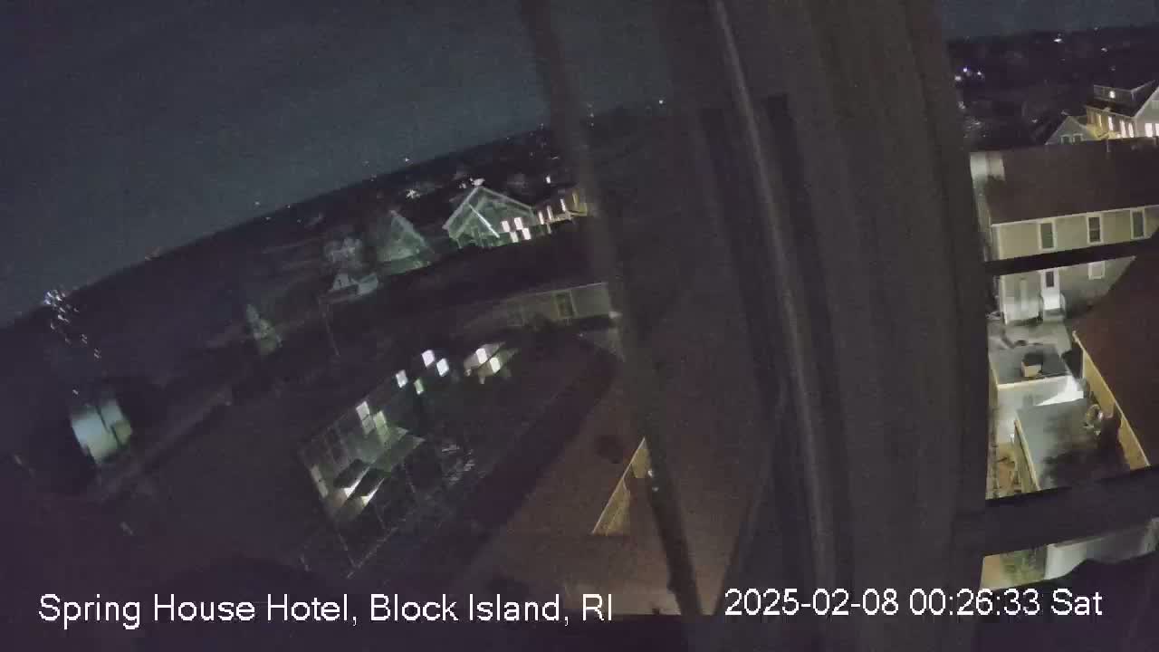 A nighttime, high-angle view from a window shows a cluster of buildings under a clear, dark sky.