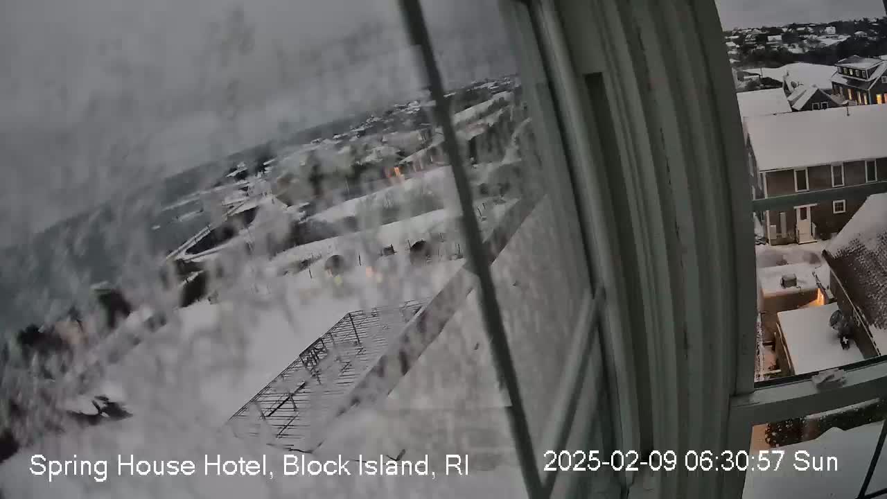 A snow-covered landscape is viewed from a window during a heavy snowfall.