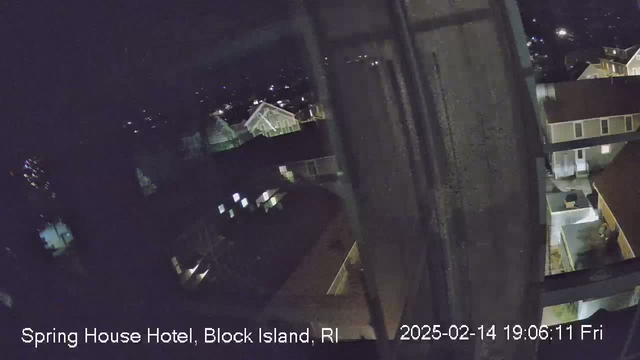 A nighttime, high-angle view from a building shows several other buildings and the surrounding area, dimly lit under a dark sky.