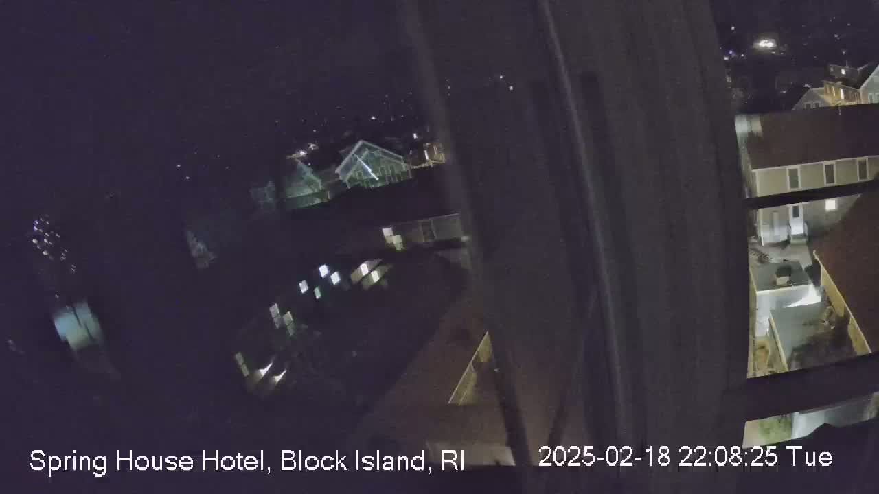 A nighttime view from a window shows several buildings and a small pool area, under a clear sky.