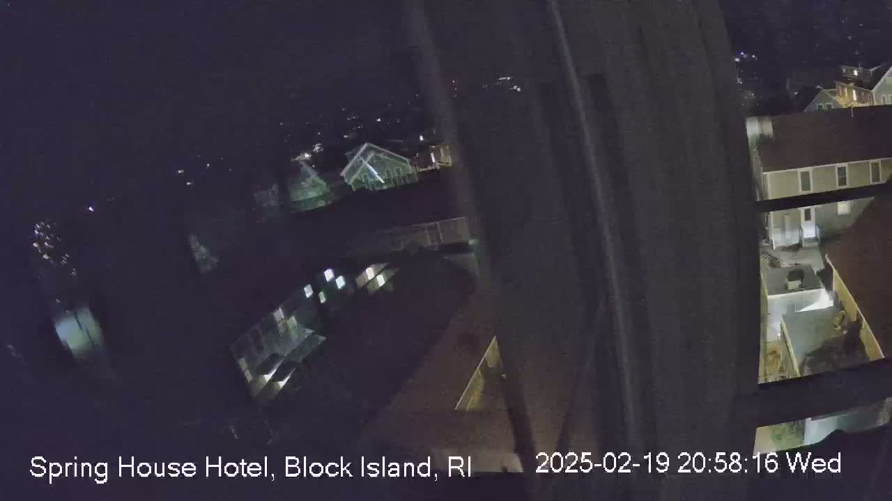 A nighttime, high-angle view from a window shows several buildings with some lights on.