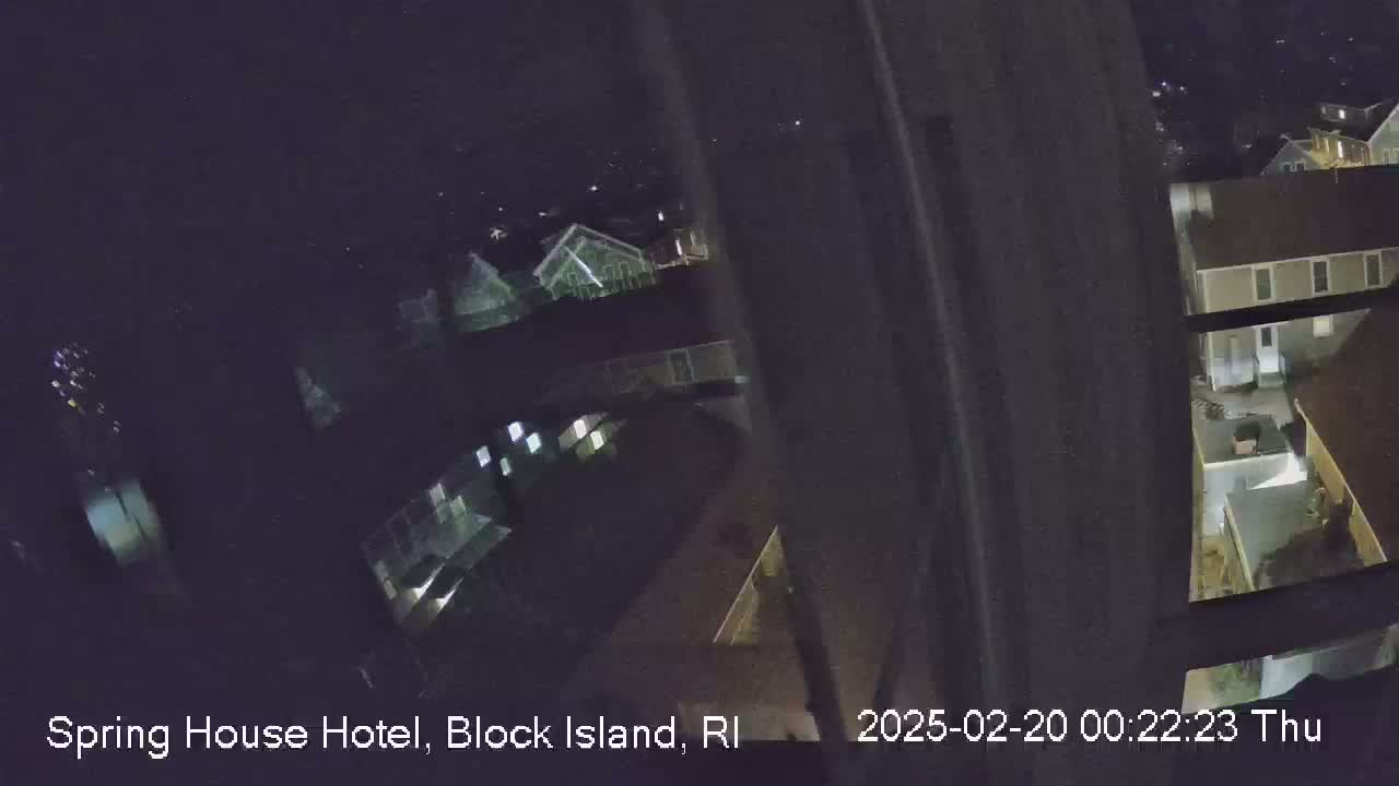 A nighttime, high-angle view from a window shows several buildings and a dark yard.