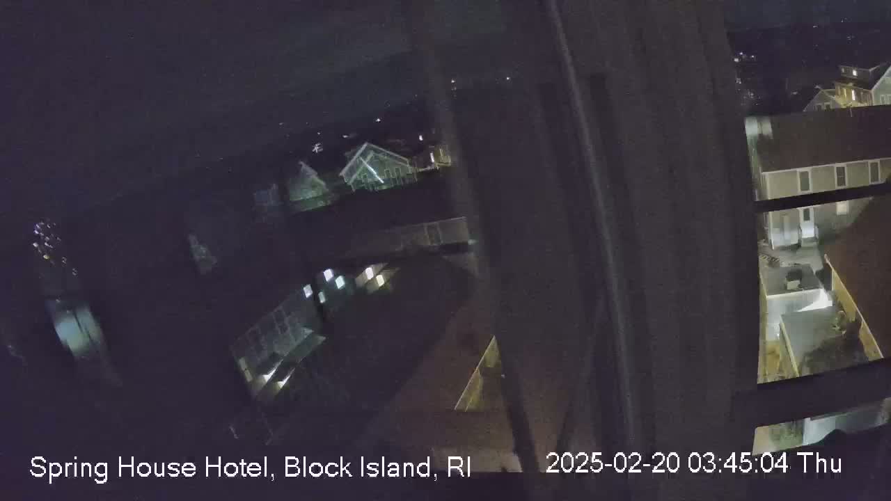 A nighttime view from a window shows several buildings with illuminated windows.