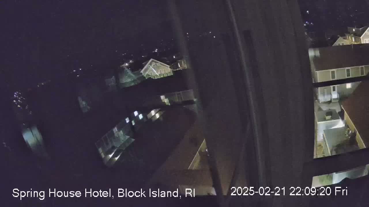 A nighttime view from a window shows several illuminated buildings and a dark sky.