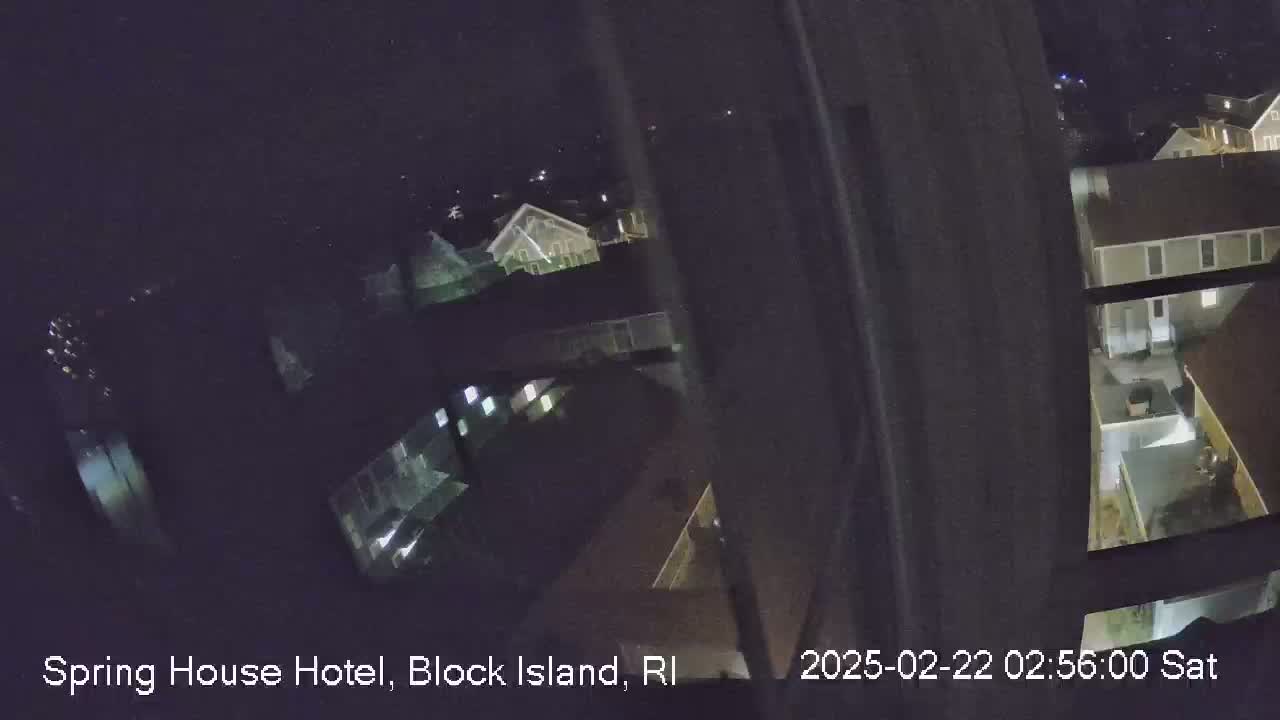A nighttime, high-angle view from a window shows several illuminated buildings and a courtyard.