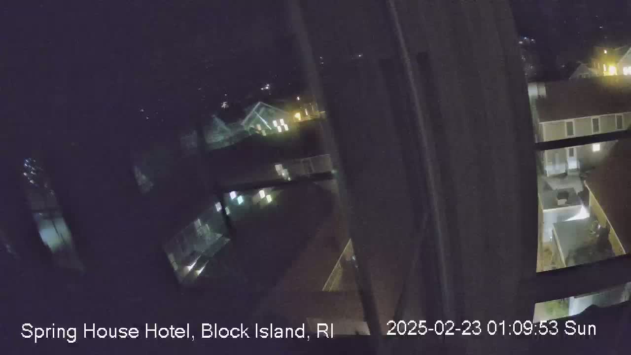 A nighttime, outdoor view from a window shows several buildings with some lights on.