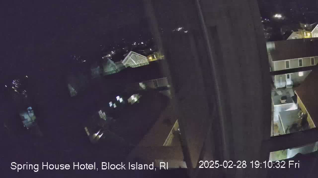 A nighttime, high-angle view from a window shows a cluster of buildings with some lights on.