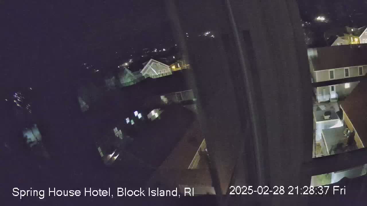 A nighttime, high-angle view shows a residential area with several buildings illuminated by exterior lights.
